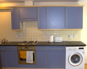 伦敦Spacious 2BR flat in Central London near Elephant and Castle station的厨房配有蓝色橱柜和洗衣机。