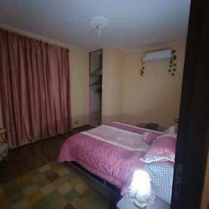 Qaryat ShākūshTwo pools four bedrooms private villa的一间卧室配有一张带粉红色棉被的床