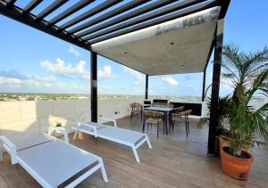 科苏梅尔Brand new condo with Rooftop pool的屋顶上设有白色长椅和桌子的庭院