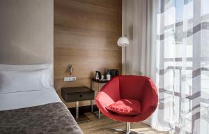 科尔多瓦NH收藏阿米斯塔德科尔多瓦酒店的一张红色椅子坐在房间床边