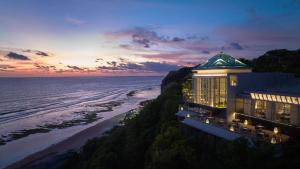 乌鲁瓦图Umana Bali, LXR Hotels & Resorts的海边悬崖上的建筑