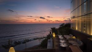 乌鲁瓦图Umana Bali, LXR Hotels & Resorts的海滩景公寓大楼设有桌椅