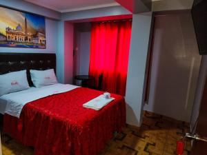 利马Hostal Paris的一间卧室配有一张带红色毯子和红色窗帘的床