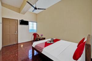 钦奈OYO Flagship 92943 Guna Residency的一间卧室配有一张带红色枕头的床和一扇门