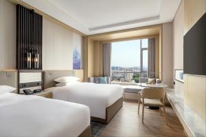 汕尾汕尾海丰万怡酒店的酒店客房配有两张床和一张书桌
