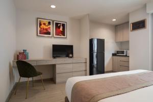 曼谷阿斯皮拉卢阿卢迪公寓的一间卧室配有一张床、一张书桌和一台冰箱