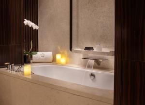 北京北京饭店诺金-王府井的浴室配有带2把蜡烛和2把蜡烛的浴缸。