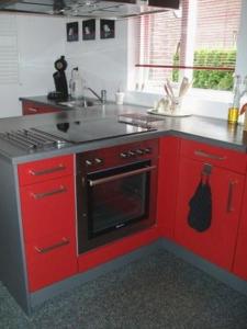 奥门卡普蒂姆度假屋的厨房配有红色橱柜和炉灶烤箱