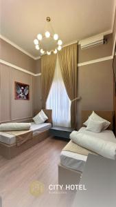 TürkistanCity Hotel Turkistan的酒店客房设有两张床和吊灯。