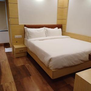德奥加尔Hotel Taj Akash的一张带白色床单和枕头的床