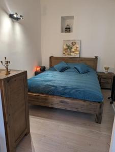 芒通2 pièces , Centre ville , 100 mètres des plages.的一间卧室配有一张带蓝色床单的木床。