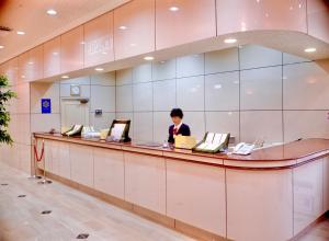 冈山Okayama Ekimae Universal Hotel的站在大厅柜台的女人