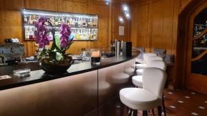 慕尼黑Hotel Lechnerhof Unterföhring的一间酒吧,配有白色椅子和紫色花卉柜台
