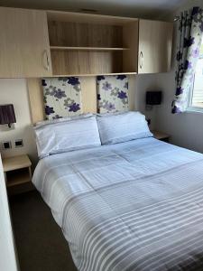 坦伯利GDs Luxury Caravan Hire Turnberry Holiday Park的一间卧室配有一张带白色床单的大床