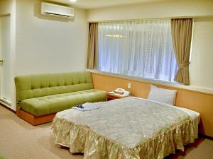 松江市Matsue Universal Hotel的一间卧室配有一张床、一张沙发和一个窗口