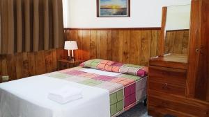 圣萨尔瓦多Hotel Manantiales El Salvador的一间小卧室,配有一张床和一个梳妆台