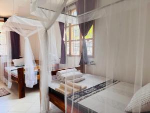 莫希Karibu Africa Home的一间卧室配有一张天蓬床和窗户