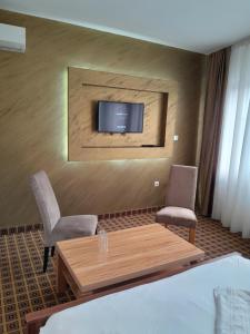 萨拉热窝Hotel PEKING的配有桌子和两把椅子以及电视的房间