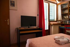 卡斯托里亚Carte Postale的一间卧室配有一张床和一张书桌上的电视