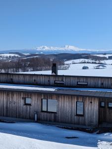 美瑛町Meiji no Okano Yado的一座有雪的木结构建筑