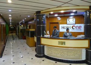 卡拉奇Hotel One Karachi的两个坐在大堂旅馆柜台的男人