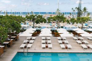檀香山Hilton Vacation Club The Modern Honolulu的酒店游泳池设有白色躺椅和码头