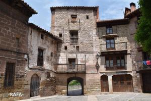 摩拉鲁比罗Vista al Castillo de Mora de Rubielos VUTE-22-036的一座古老的石头建筑,设有大门和阳台
