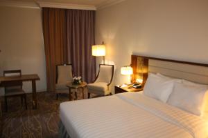 利雅德利雅得爱慕酒店的酒店客房,配有一张床、一张桌子和椅子