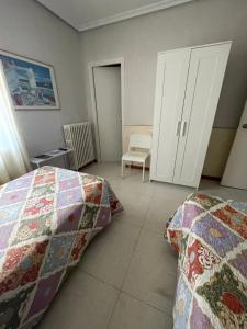 圣阿德里安Hostal Ochoa的一间卧室配有两张床、一个橱柜和椅子