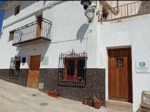 HinojaresCasa De Juanita Vivienda Rural的白色的建筑,设有木门和阳台