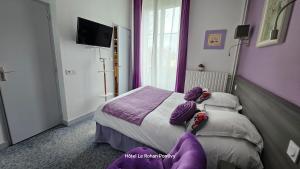 蓬蒂维Hôtel Le Rohan Charme et Caractère的一间卧室配有一张带紫色枕头的床