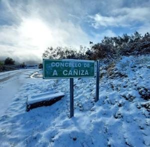 OrosoCasa Rural Cabo de Aráns的雪覆盖道路一侧的绿色街道标志