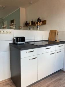 爱尔福特Wohnen im Grünen bei der Töpferei的厨房配有白色橱柜和黑色台面