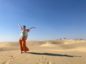 斋沙默尔Marigold Homestay的站在沙漠中的沙子上的女人