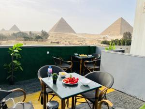 开罗Capital Of Pyramids Hotel的一个带金字塔的阳台的桌椅