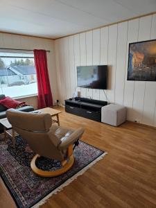 特罗姆瑟Tønsvik enebolig的客厅配有椅子和平面电视