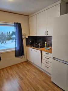 特罗姆瑟Tønsvik enebolig的厨房配有白色橱柜、水槽和窗户。
