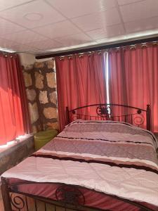Ad DimnahHeritige Inn Jordan的红色窗帘的房间的一张床位