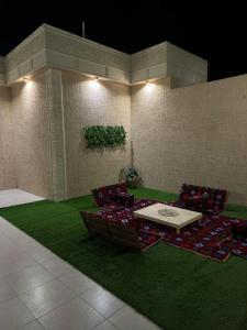 海米斯穆谢特الجود مخيم شقة استراحة بيت的一间绿色地毯上配有椅子和桌子的房间