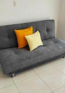库库塔Acogedor Apartaestudio cerca al aeropuerto的灰色的沙发上配有两个橙色枕头