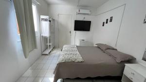 福塔莱萨Pousada Mar & Sol的一间小卧室,配有一张床和电视
