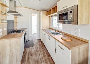 梅布尔索普Towervans Caravan Park的厨房配有白色橱柜、水槽和微波炉