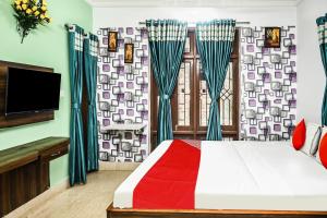 加尔各答OYO Flagship Shraddha Residency 2的一间卧室配有床、电视和窗帘