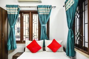 加尔各答OYO Flagship Shraddha Residency 2的窗户客房内的一张带红色枕头的床
