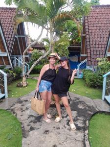 蓝梦岛D'Yuki Huts Lembongan的两个女人在房子前面摆一张照片