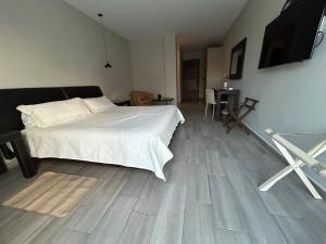 坎昆Suites Athos4的卧室配有白色的床,铺有木地板