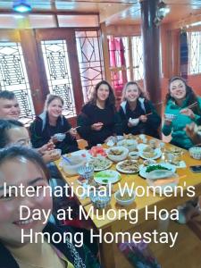 萨帕Muong Hoa Hmong Homestay的一群坐在餐桌旁吃食物的妇女
