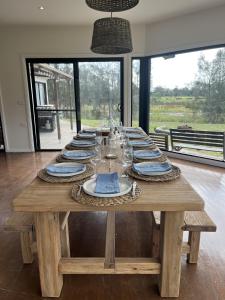 Salt AshThe Ranch - Coastal Farmhouse midway to Newcastle Airport and Beaches的一张长木桌子,上面有盘子和玻璃杯