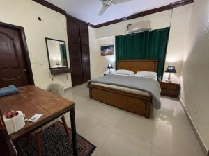伊斯兰堡Backpackers Hostel Islamabad的一间卧室配有一张床、一张桌子和绿色窗帘