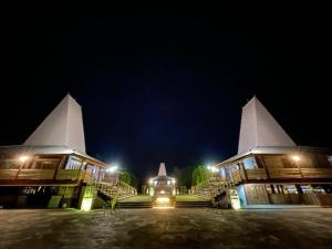LokokakiRumah Budaya Sumba的一座晚上有两座白色塔楼的建筑